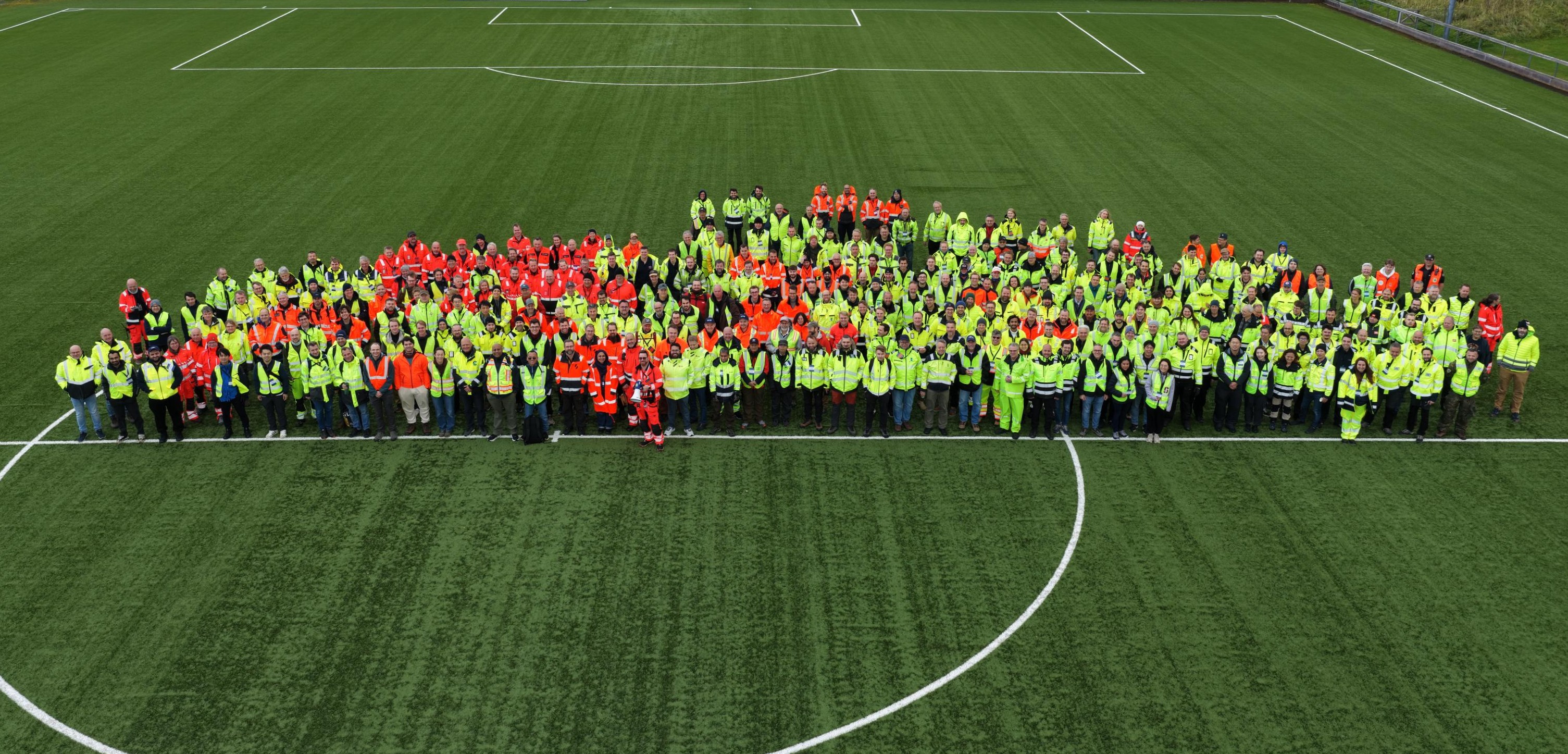 302 people dressed in safety gear, standing on a football field